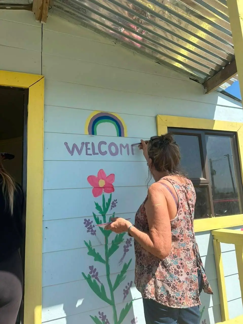 A volunteer painting the welcome mural on the cabin wall