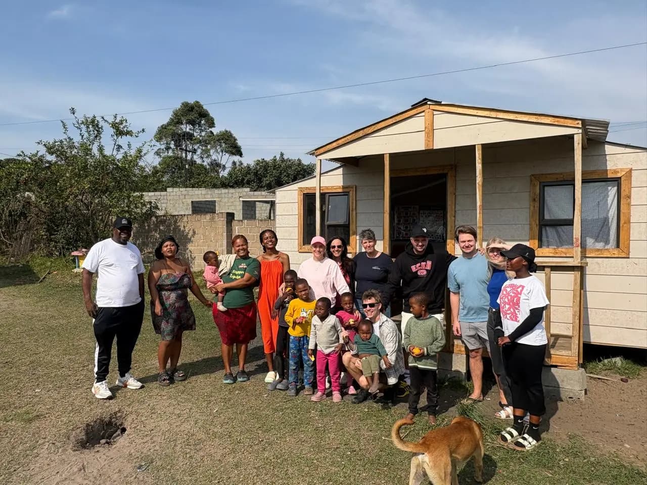 Volunteers and children gathered in front of the house