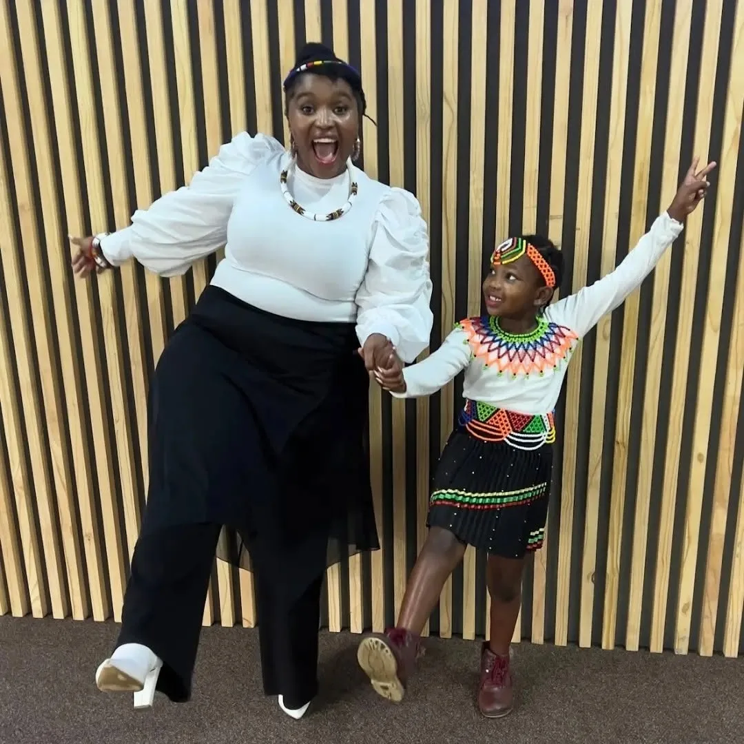 A mother and daughter in traditional beadwork, dancing together